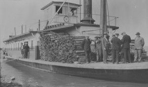 A steamship with men and a load of wooden planks on deck