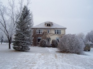A house, lawn, and trees lightly dusted with snow
