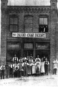 People pose for a photo in front of "The Inland Cigar Factory"