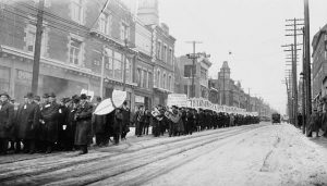 A line of people march through a street holding signs