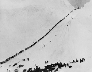A long line of people walking up a snowy hill