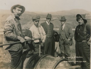 A man fills a drum with gasoline from a spigot as four others watch