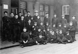 A large group of boys pose together with a man