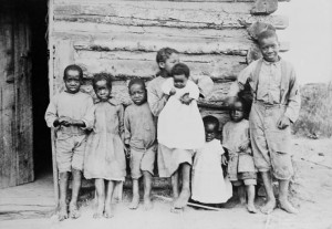 Photo of a group of young children standing against a house