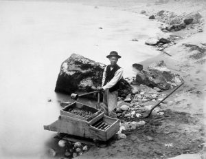 A man washes gold in a river