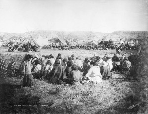 People sitting together in an open area near tent structures