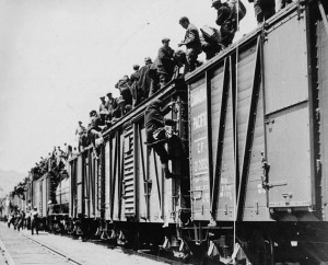 Photo of the side of a train with many people standing on top of the cars
