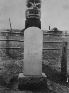 Headstone with a memorial pole extending behind it