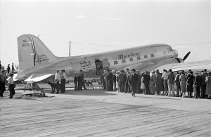 Passengers lined up outside of a plane called "The Mainliner"