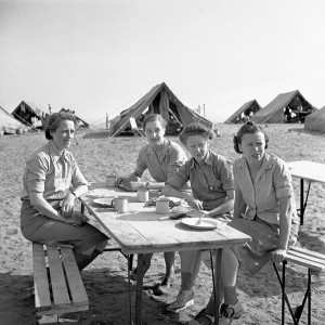 Women sit at a picnic table near tents