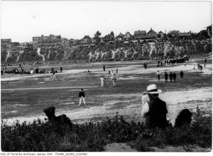 A field with people playing cricket and baseball
