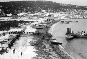 A line of people pull an aircraft onto the shore by hand