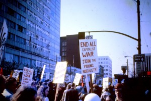 A crowd with signs reading "End all capitalist war", "Join the young socialists", and "End Canadian complicity"