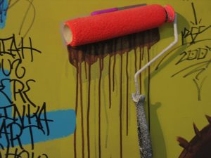 A paint roller soaked in bright red paint