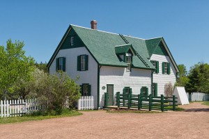 A house with white siding and green gables, shingles, fencing, and shutters