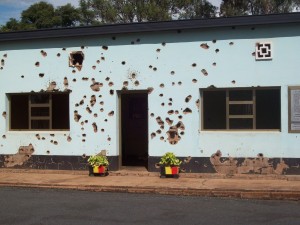 Photo of a building front riddled with bullet holes