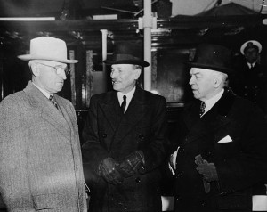 Three men stand together in discussion