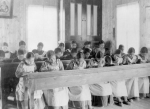 Children in matching clothes sit at long tables