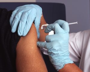 Healthcare provider injecting a client with a needle vaccination.
