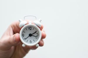tiny white alarm clock in a hand