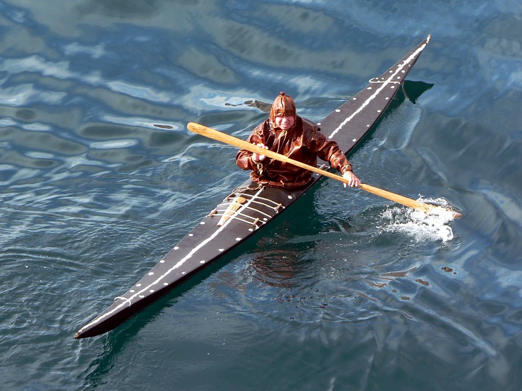 Inuit kayaker in a kayak and clothing made of seal skins.