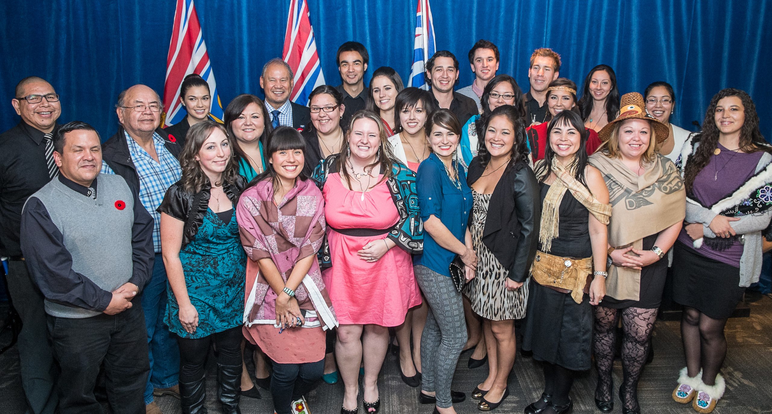 This image shows women and men, mostly young, beaming. All are well-dressed and a few are in traditional clothing.