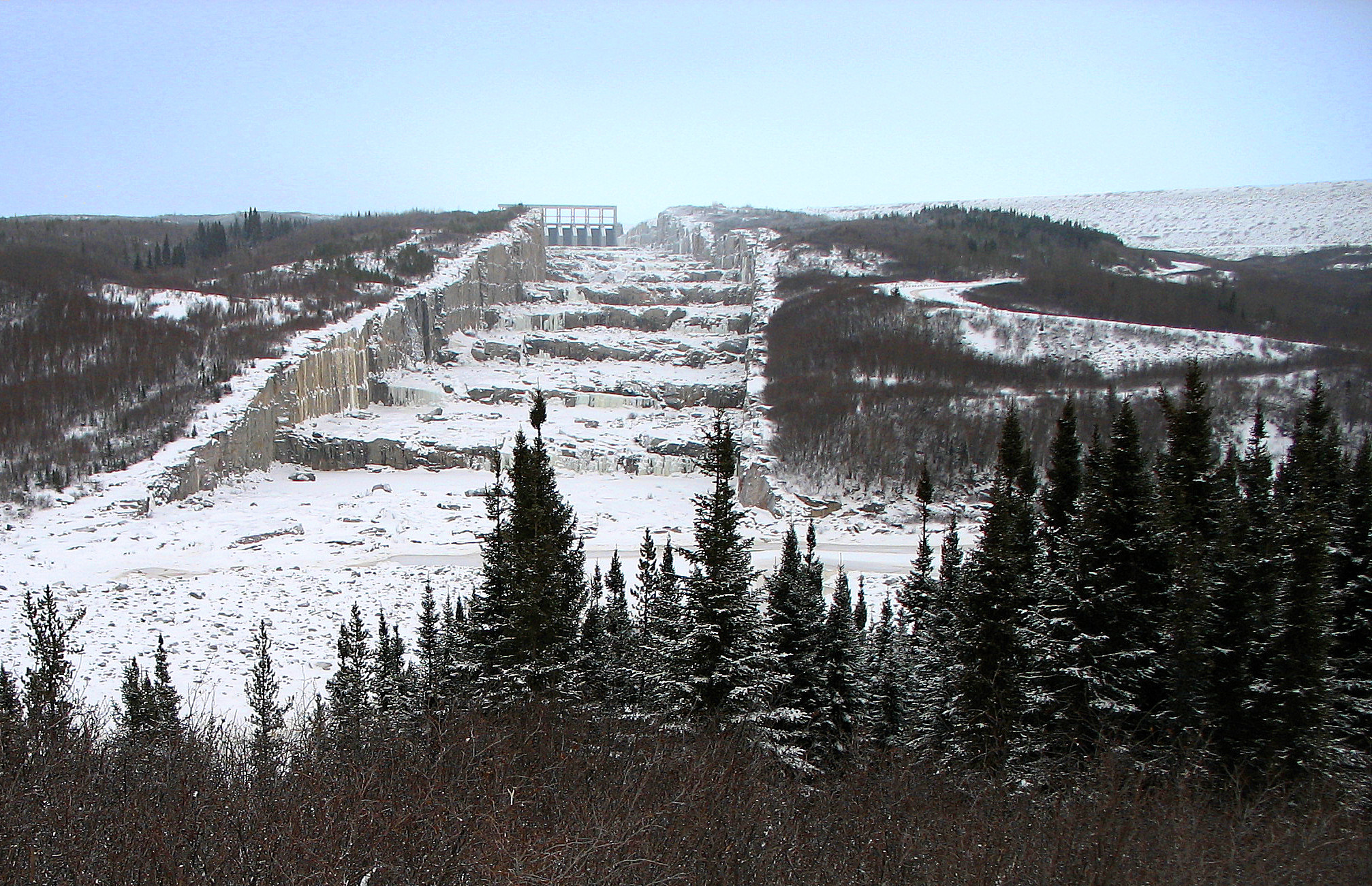 This photo shows what looks like a giant staircase, much wider than tall, covered with snow and ice, with coniferous trees on either side. It appears to be between 50 and 100 metres in width.