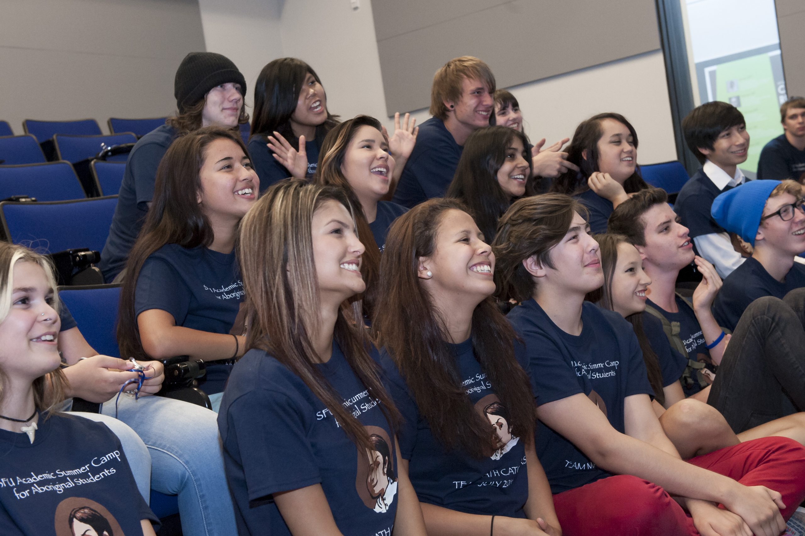 Teenagers in theatre-style seating looking joyfully at the stage.