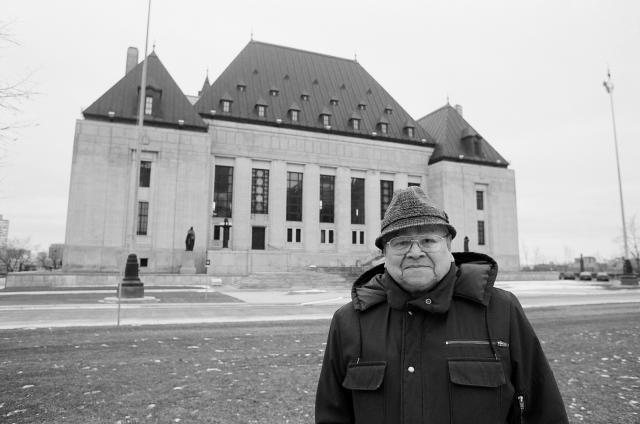 Dr. Calder is wearing a winter coat and wool cap. He looks happy and also serious.