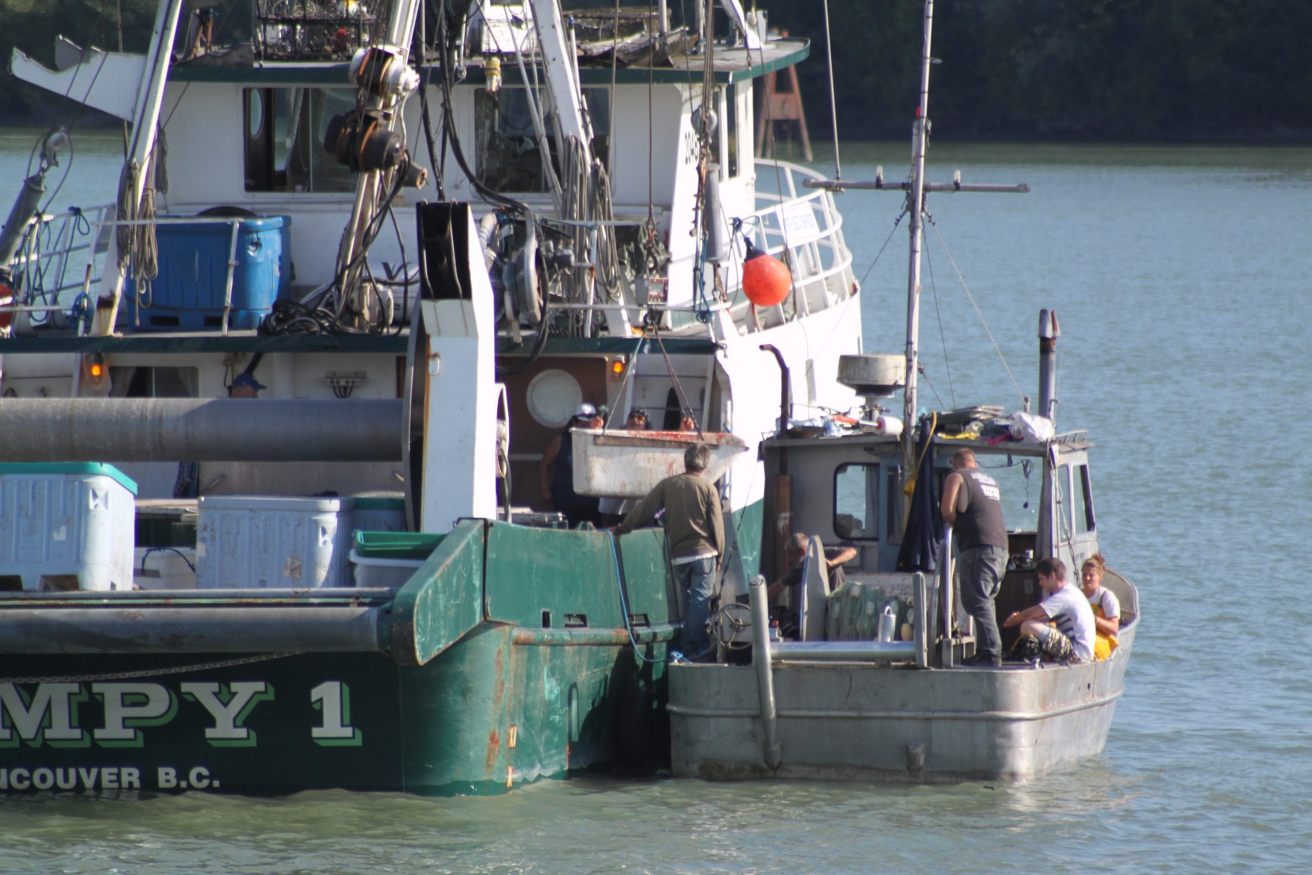 This photo shows a small fishing boat pulled up next to a larger one.