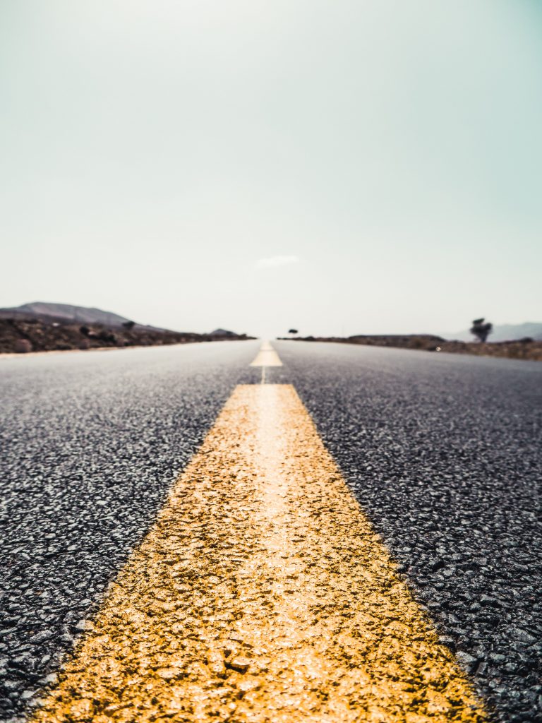 Long paved road with a yellow line down the middle. Goes off into the distance.