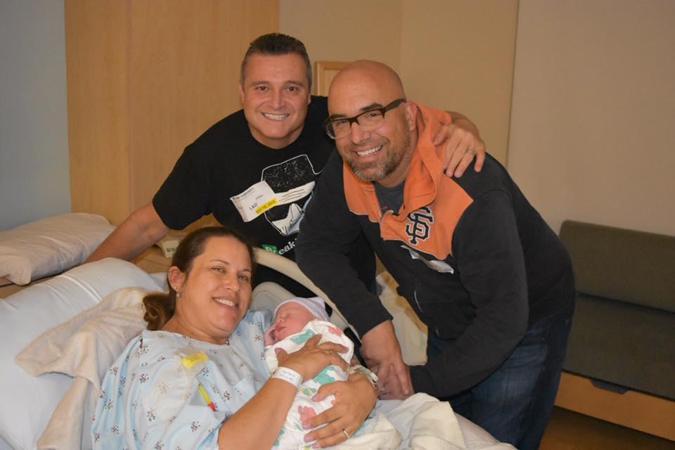 image of a same sex couple with a surrogate holding a newborn