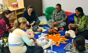 q group of women learning how to give their babies a massage