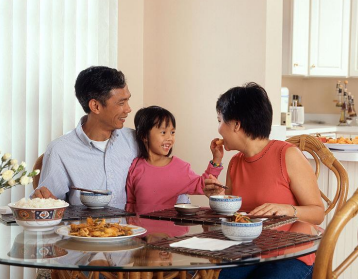 a mother, father and child sitting at a table eating