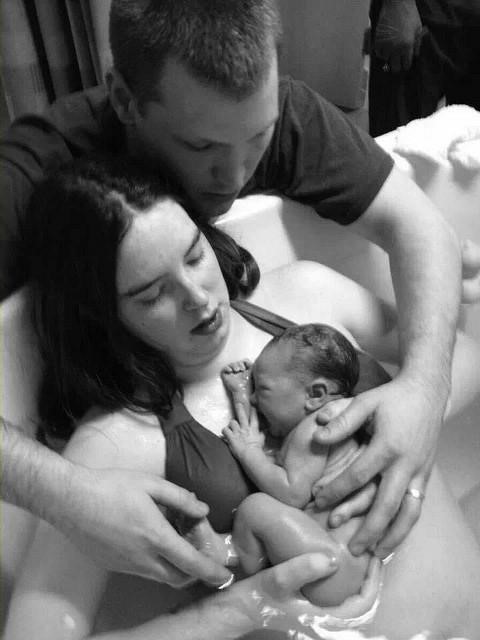 mother and father holding a newborn baby delivered using the waterbirth method