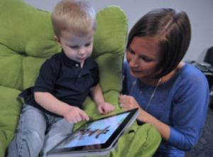 a mother looking on while her child uses a tablet
