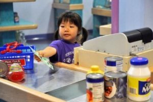 A child pretending to buy items at a toy grocery store. 