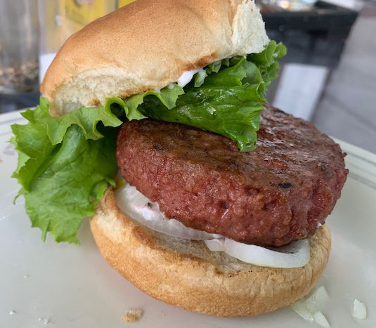 close up of a plant-based burger on a bun with lettuce and onions