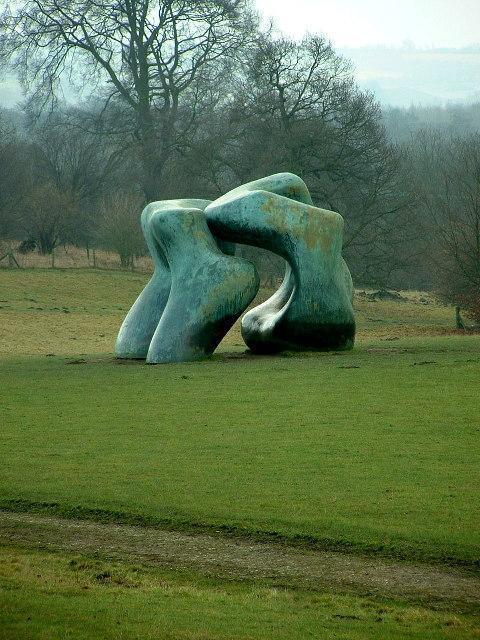 a large bronze sculpture sitting on a grassy slope