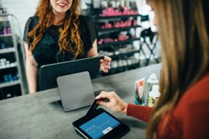 Female cashier and female customer paying with credit card