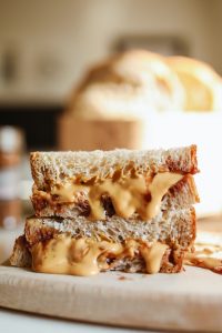 Peanut butter sandwich on a wooden plate.