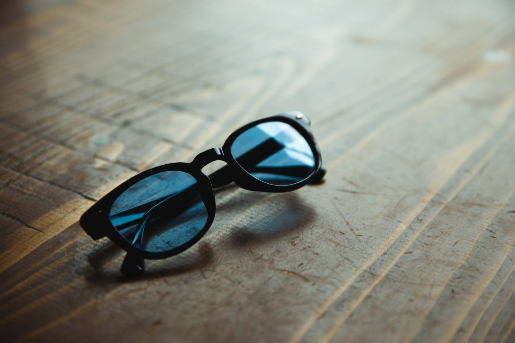 Trendy sunglasses placed on wooden table