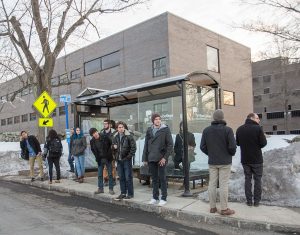 people cueing for bus at a sheltered bus stop in cold weather