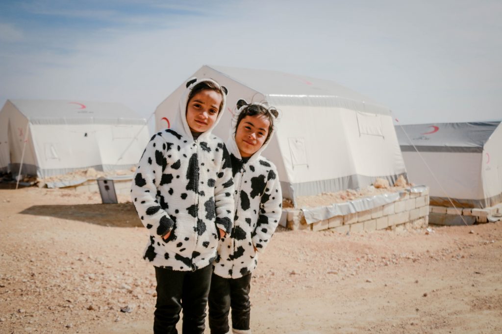 Ethnic twins looking at camera in refugee camp