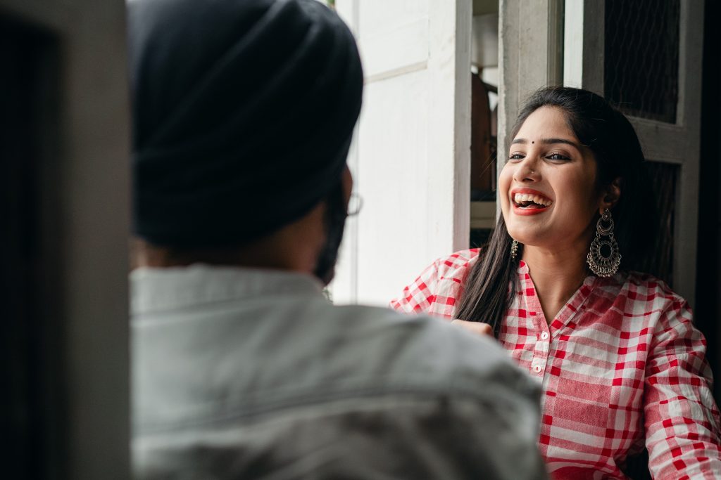 Trendy young woman laughing at joke told by man