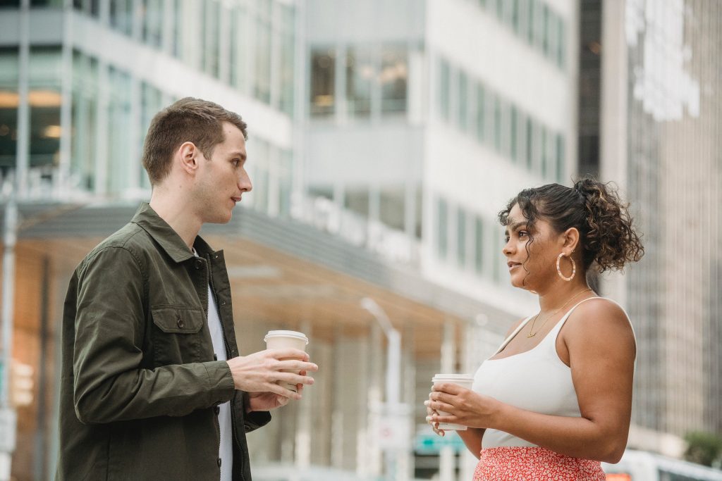 Young diverse coworkers having coffee break together on city street