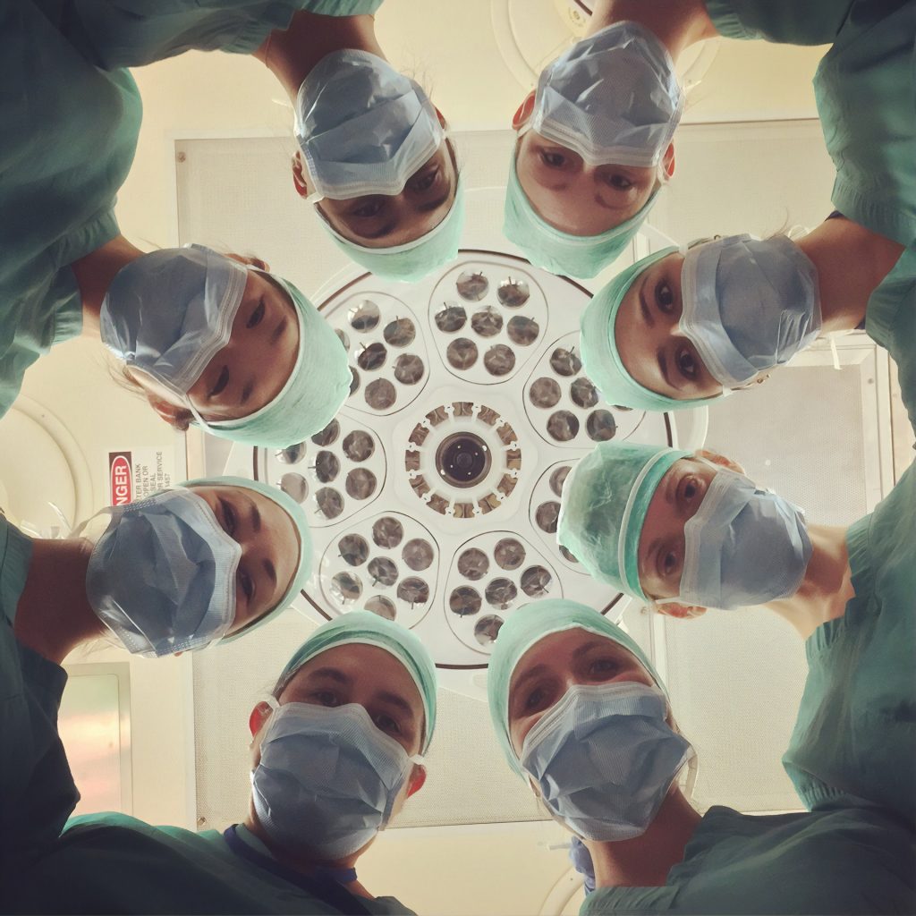 Doctors standing in a circle, wearing masks, and peering down