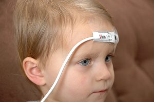 Pulse oximeter with sensor taped across forehead.