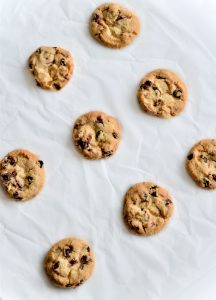Eight chocolate chip cookies on a slightly crumpled piece of white paper.