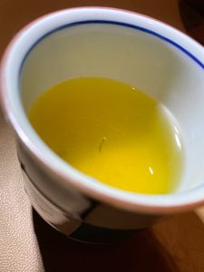 Japanese green tea in a traditional Japanese-style, blue and white checkered tea cup. A single tea stalk floats vertically in the tea.